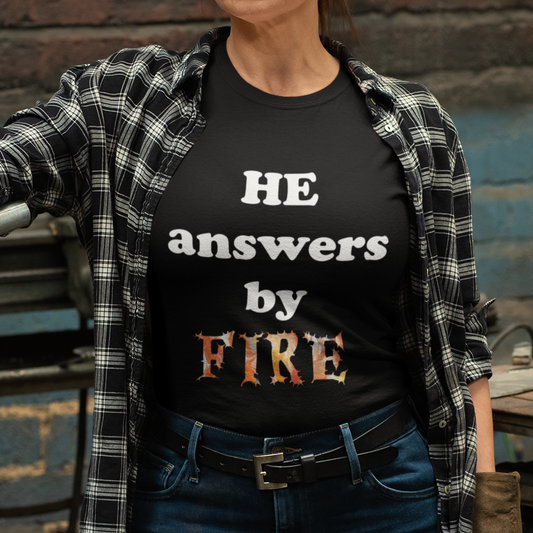 A person wearing a black unisex t-shirt with the text 'HE answers by FIRE' in white and orange.