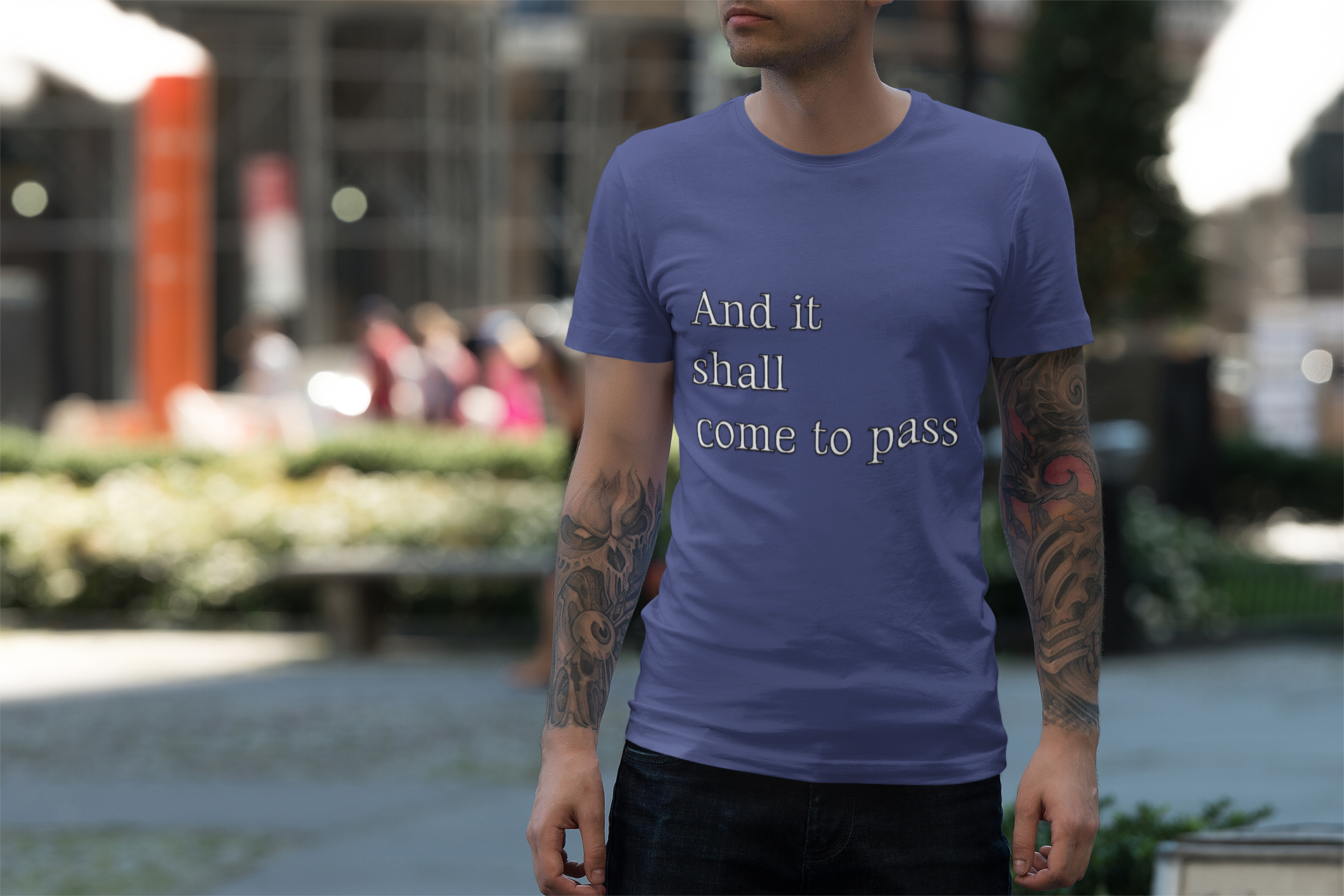 A person wearing a blue unisex softstyle t-shirt with an inspirational quote standing outdoors.
