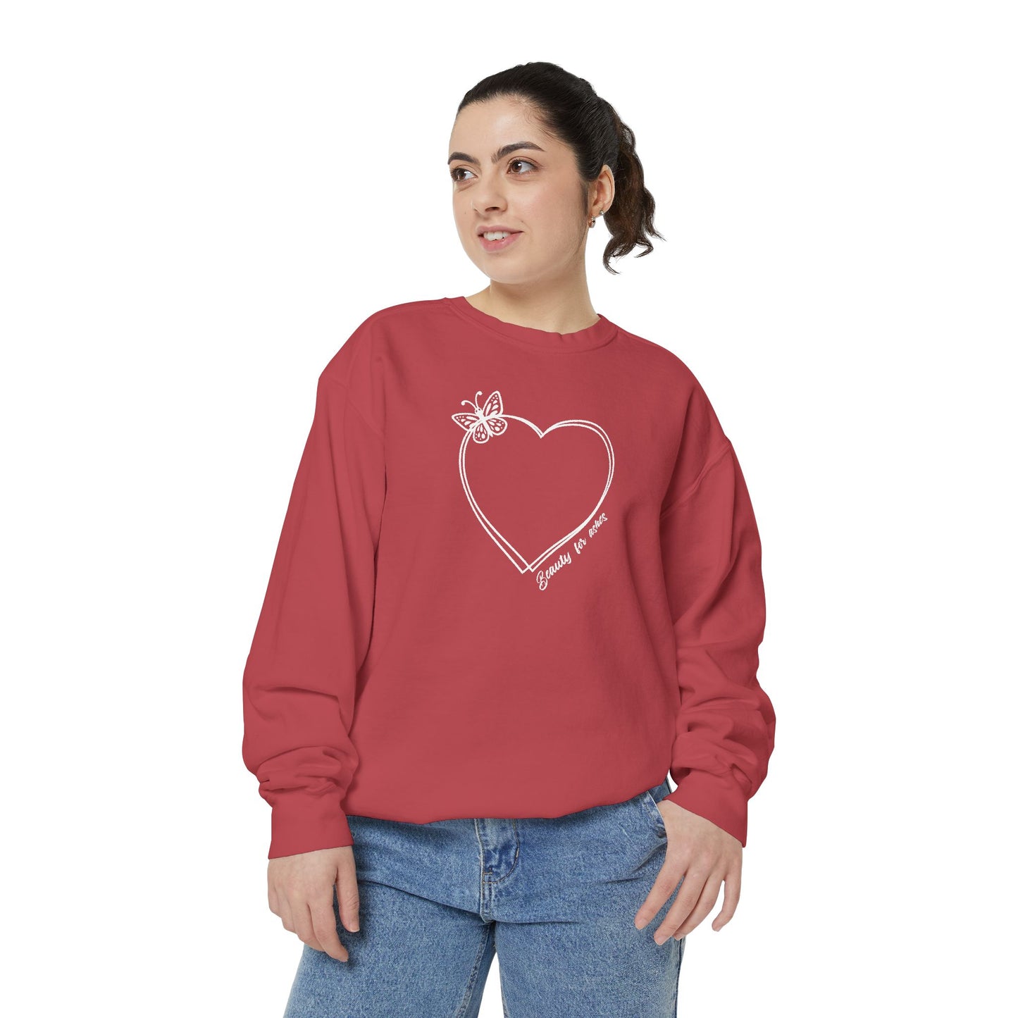 A woman wearing a coral sweatshirt with a heart design and a butterfly on it.
