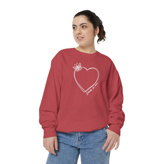 A woman wearing a coral sweatshirt with a heart design and a butterfly on it.